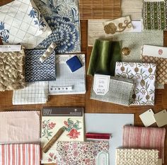 many different types of fabric and papers on a wooden table with bamboo placemats