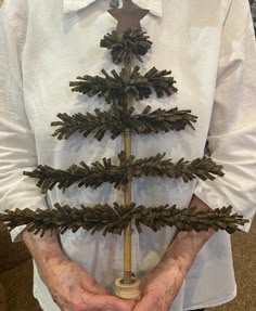 an older person holding a christmas tree made out of pine cones