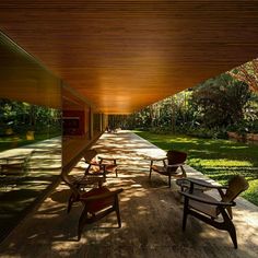 two wooden chairs sitting on top of a patio next to a lush green forest covered hillside