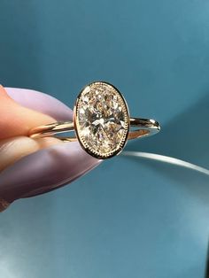 a close up of a person's hand holding a ring with a diamond in it