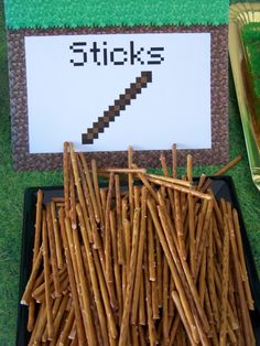 some sticks are sitting in a tray on the grass next to a sign that says sticks