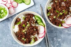 two bowls filled with rice, meat and veggies