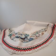 a white table cloth with red, green and blue trim on it sitting on top of a counter