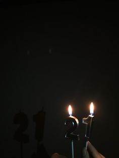 someone is holding two candles in the shape of number twenty and one that has been lit