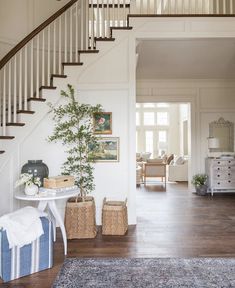 a living room with stairs and a rug on the floor, next to a table