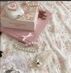 there is a pink box on the bed with pearls and other items around it,