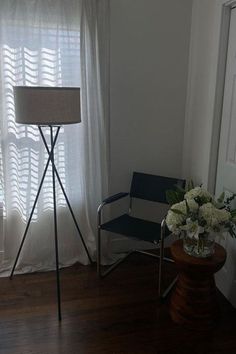 a room with a chair, lamp and flowers in it