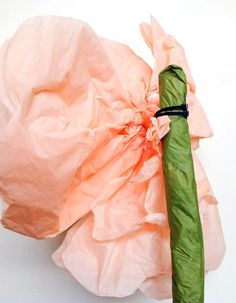 an umbrella wrapped in pink tissue paper on top of a white surface with a green handle