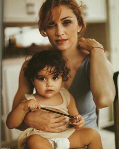 a woman combing a child's hair while sitting on a chair in front of a mirror