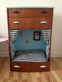 a child's bed made out of a wooden cabinet with black and white checkered sheets