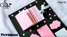 an open book with pink and white flowers on it, next to some cards that are folded