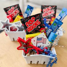 an assortment of snacks and candy in small baskets on top of a wooden table with american flag decorations