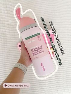 a hand holding up a pink foam bottle in front of a white sheet with the words on it