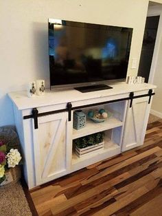 a flat screen tv sitting on top of a white entertainment center next to a wooden floor