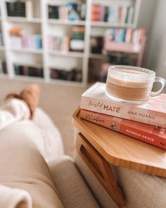 a stack of books sitting on top of a wooden table next to a coffee cup