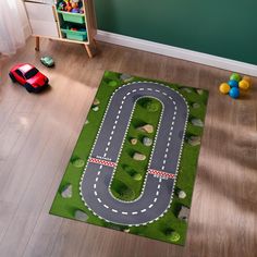 a child's play area with a toy car track on the floor and green grass