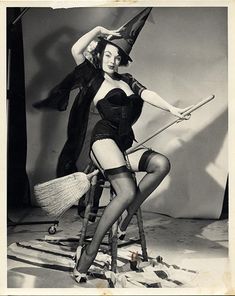 an old photo of a woman dressed as a witch on a stool with a broom