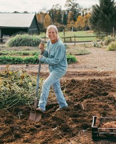 an older woman holding a shovel in the dirt