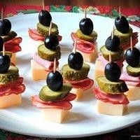 an assortment of appetizers on a plate with toothpicks and olives