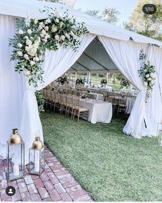 an outdoor wedding tent set up with white flowers and greenery