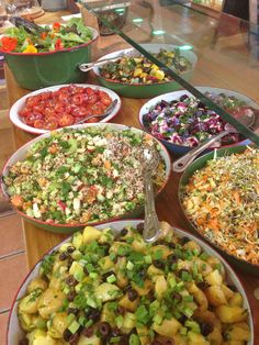 a table topped with lots of different types of salads and bowls filled with vegetables