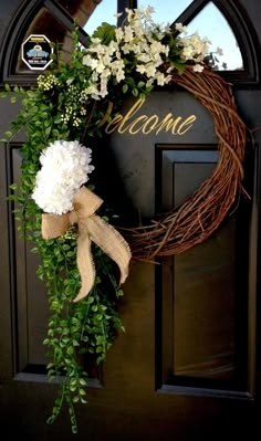 a wreath with white flowers and greenery hangs on the front door