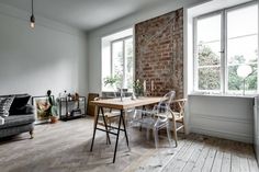 a living room filled with furniture and a wooden table in front of a brick wall