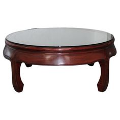 a glass top coffee table with wooden legs and an oval shaped base in the middle