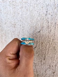 a hand holding two rings with turquoise stones on them and a diamond in the middle