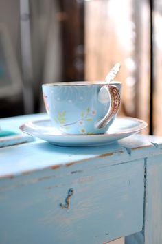 a teacup and saucer sitting on top of a blue table with an ornate design