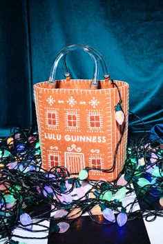 an orange handbag sitting on top of a pile of stringed up christmas lights