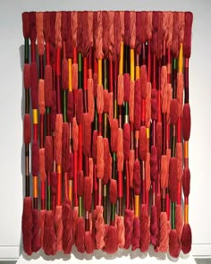 an art piece made out of red yarn and crochet hooks hanging on a wall