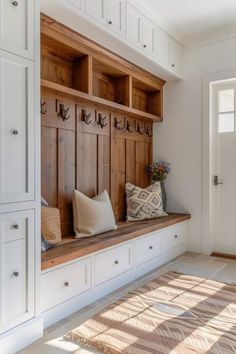 a wooden bench sitting in the middle of a room with white cupboards and drawers