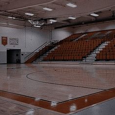 an empty basketball court with orange seats