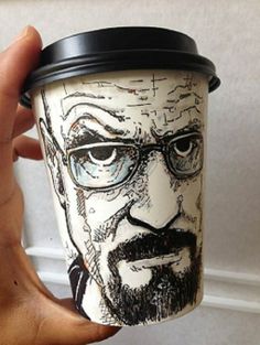 a hand holding a coffee cup with a drawing on it