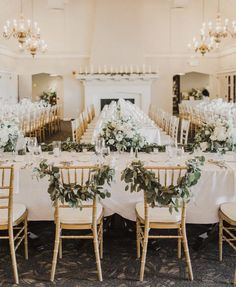 the tables are set up with white flowers and greenery for an elegant wedding reception