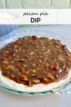 a pie with pecans on top is sitting on a glass platter and has the words pecan pie dip in front of it