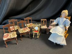 a doll sitting in a chair next to several miniature chairs