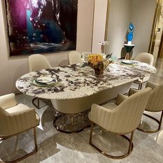 a dining room table with chairs around it and a painting on the wall behind it