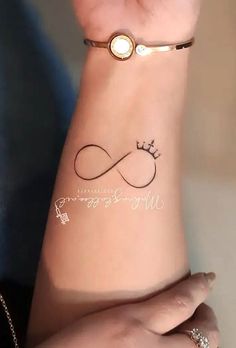 a woman's arm with a tattoo on it that has an infinite sign and a crown