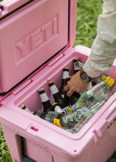 a man is holding a pink cooler full of beer