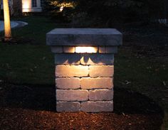 a light shines on the side of a brick wall in front of a house