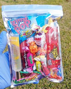 a person in blue gloves holding up a bag filled with candy