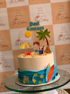 there is a cake that has been decorated with people and beach scenes on it, sitting on a table