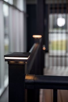 a close up of a light on the side of a railing near a building with windows