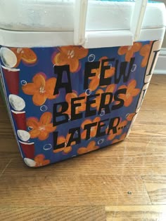 a cooler with an orange flower design on the front and bottom, sitting on a wooden floor