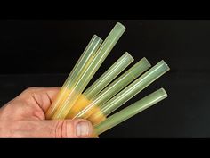 a hand is holding some green and yellow plastic straws