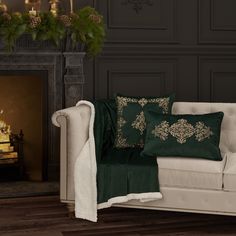 a white couch sitting next to a fireplace covered in green pillows and throw blankets on top of it