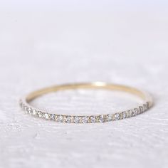 a gold wedding band with small diamonds on it, sitting on a white tablecloth