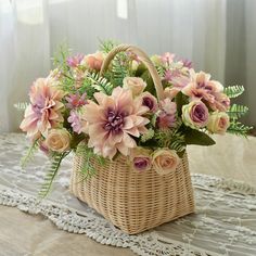 a wicker basket filled with pink flowers on a lace doily covered tablecloth